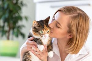 Smiling-woman-in-white-shirt-kissing-and-hugging-with-tenderness-and-love-cat
